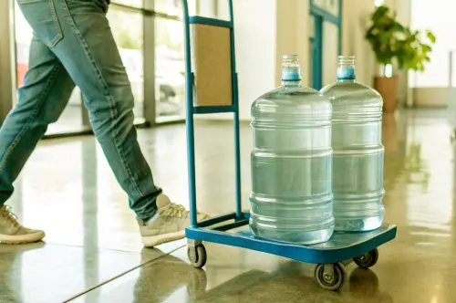 Courier wheeling two large water bottles on a trolley